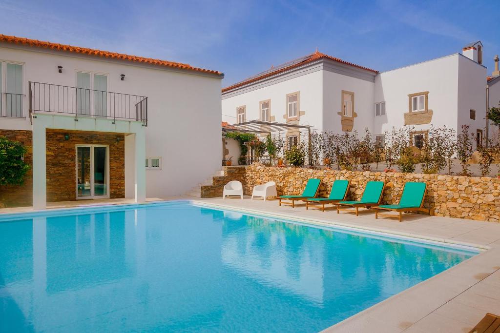 a swimming pool with chairs and a building at Casa de Valcova in Canedo