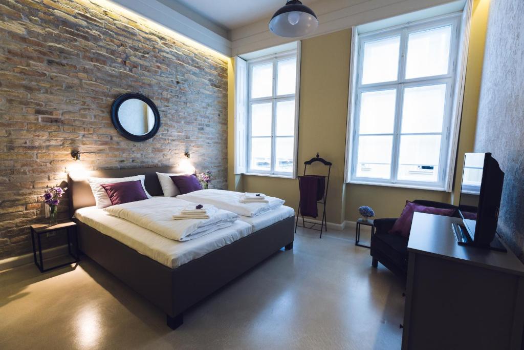 ブダペストにあるヘリテージ ホーム アパートメントのレンガの壁、ベッド付きのベッドルーム1室