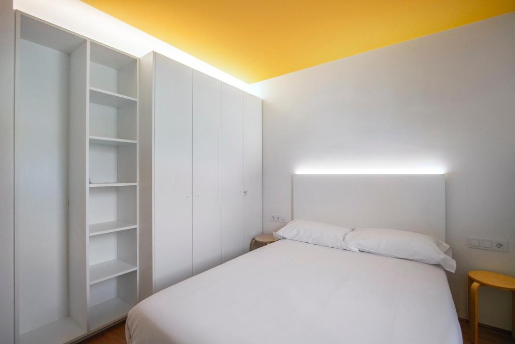 a bedroom with a white bed and a yellow ceiling at Ca l'Aiet in La Pobla de Lillet