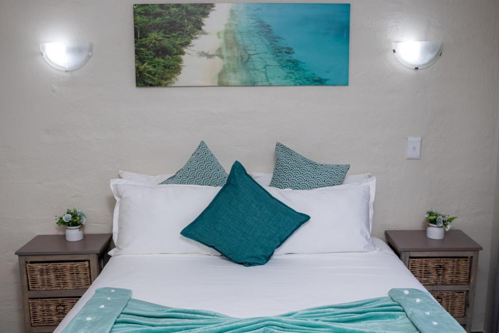 łóżko z białymi poduszkami i zdjęciem plaży w obiekcie Hillas Ridge Guesthouse w mieście Vanderbijlpark