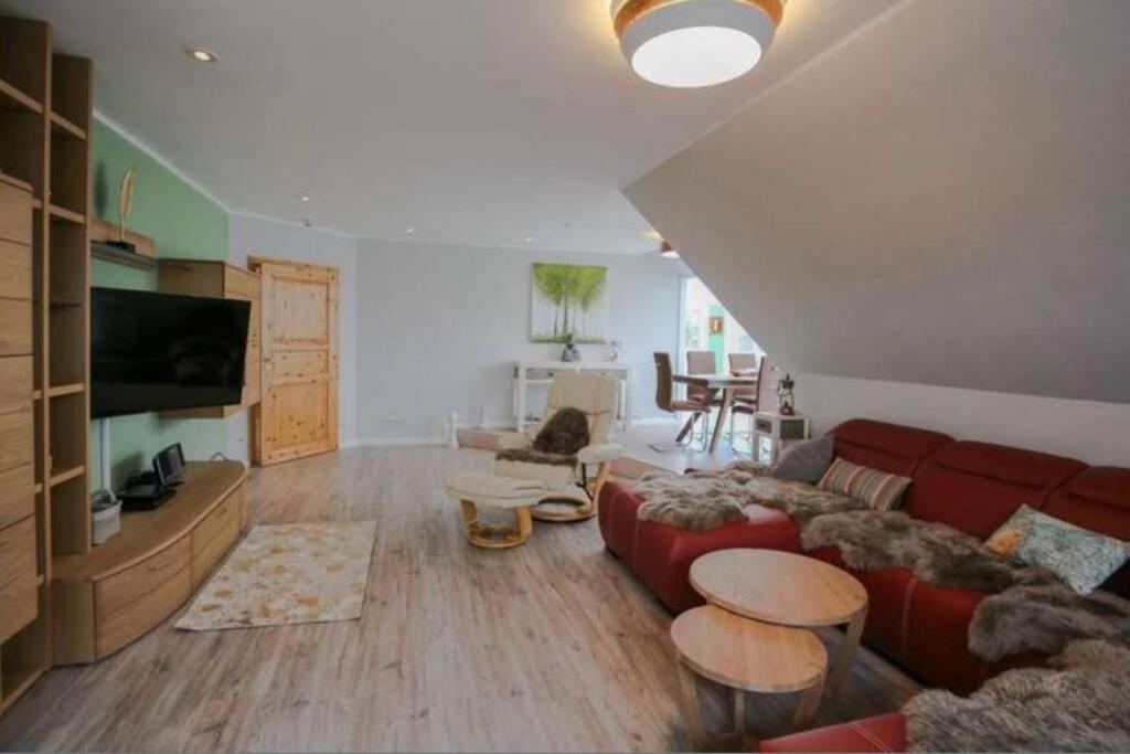 a living room with a red couch and a table at Schöne ruhige Ferienwohnung für die ganze Familie in Risum-Lindholm