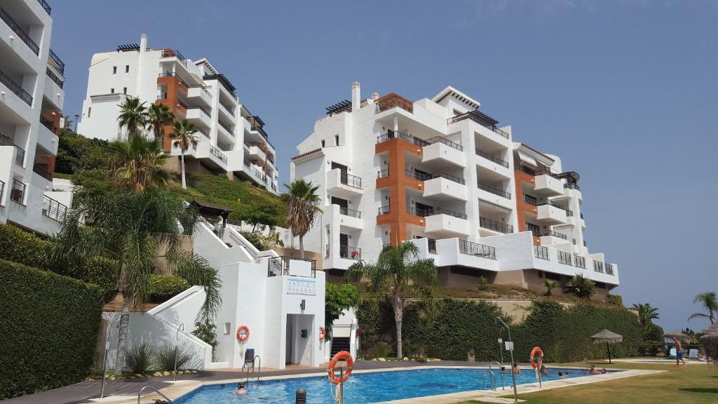 twee hoge witte gebouwen naast een zwembad bij El sol Espanol in Torrox Costa