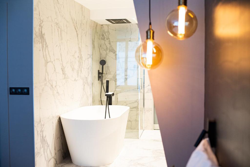 a bathroom with a white tub and a shower at L’atelier 1927, au cœur de Reims in Reims