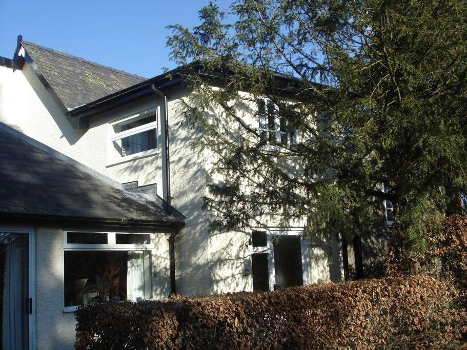 a white house with a hedge in front of it at Kwerky Cottage in North Lydbury