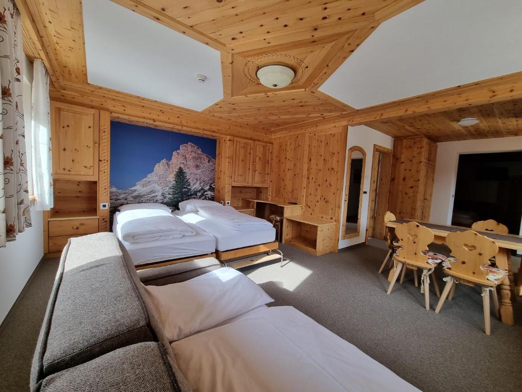 コルフォスコにあるHotel Borestのベッド3台、テーブル、デスクが備わる客室です。
