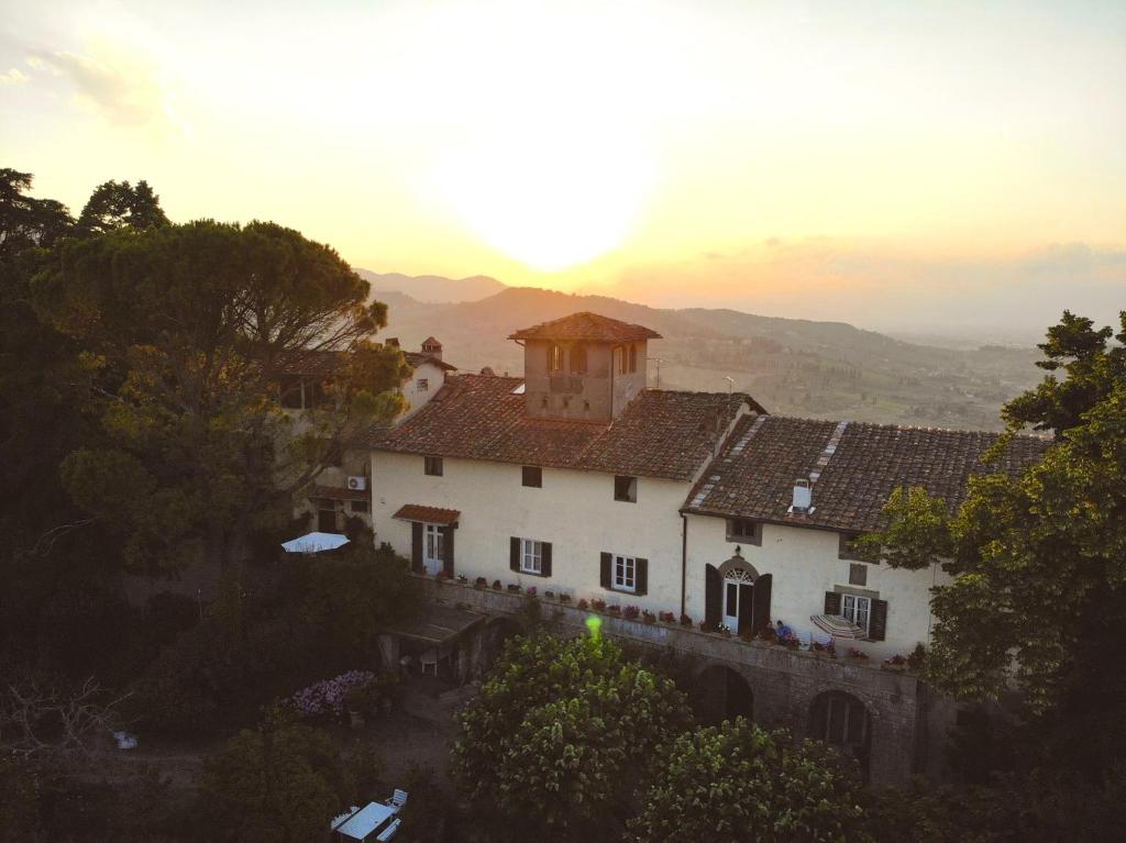 un grande edificio bianco in cima a una collina di B&B La Rocca a Carmignano