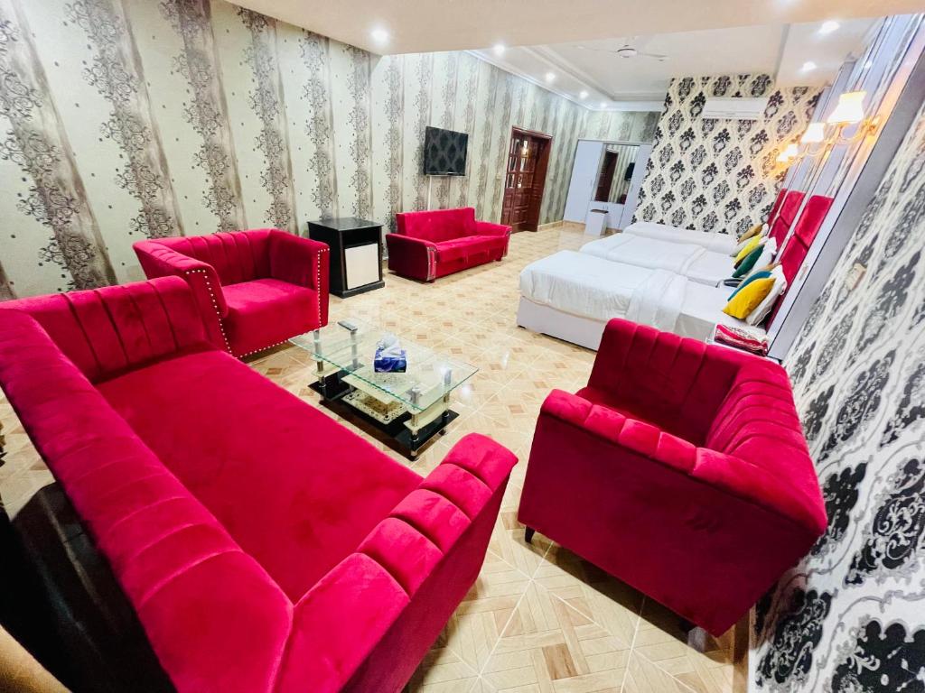 ein Wohnzimmer mit roten Möbeln und einem Bett in der Unterkunft Hotel Serena Palace in Multan