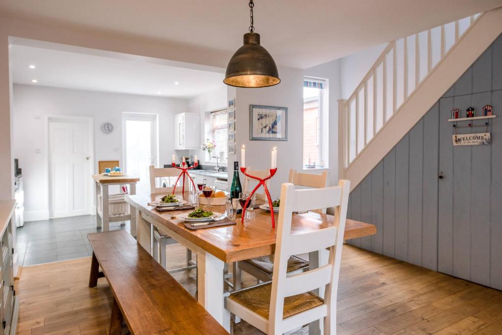 Sandy Lane Cottage in Reydon by Air Manage Suffolk في ساوثوولد: مطبخ وغرفة طعام مع طاولة وكراسي خشبية
