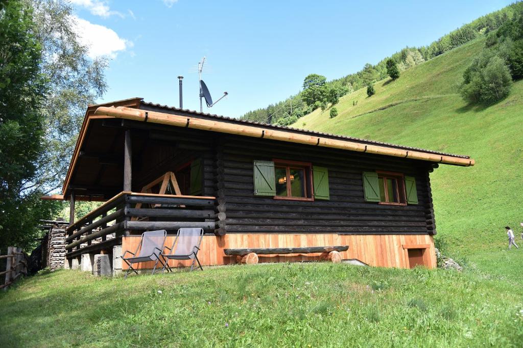 a cabin on a hill with two chairs in front of it at Berghütte Ahrntal in San Giovanni in Val Aurina