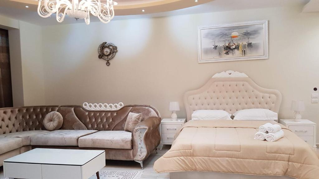 1 dormitorio con 2 camas, sofá y lámpara de araña en Apartments Romario, en Sarandë