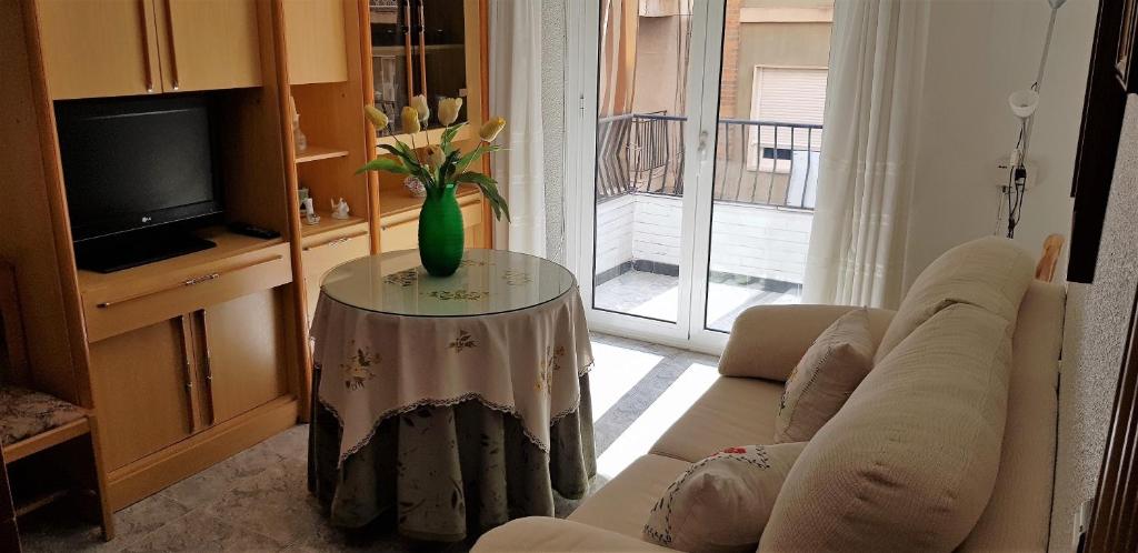 sala de estar con sofá y mesa con jarrón en Apartamento Armonía:céntrico, tranquilo y acogedor, en Elda