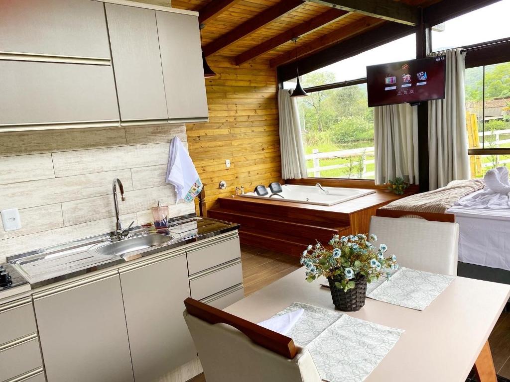 a kitchen with a table and a sink and a counter at Cabana Flor de Cactos in Praia Grande