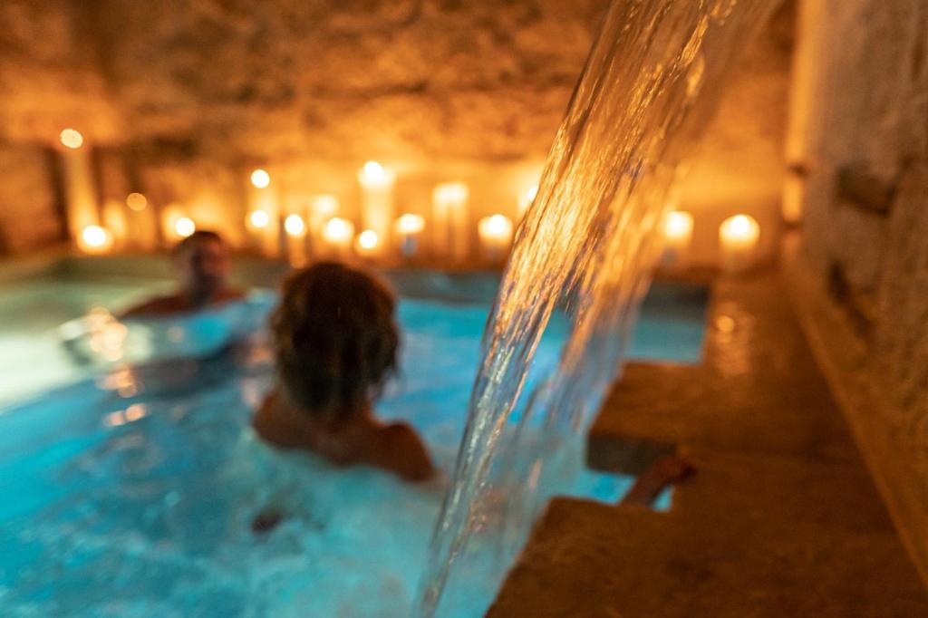 a man and a woman in a swimming pool with candles at Lanime - Bed in Spa in Sogliano Cavour