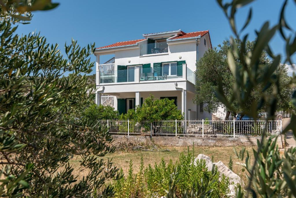 a white house on the beach with trees at Apartmani Lejla in Poljica
