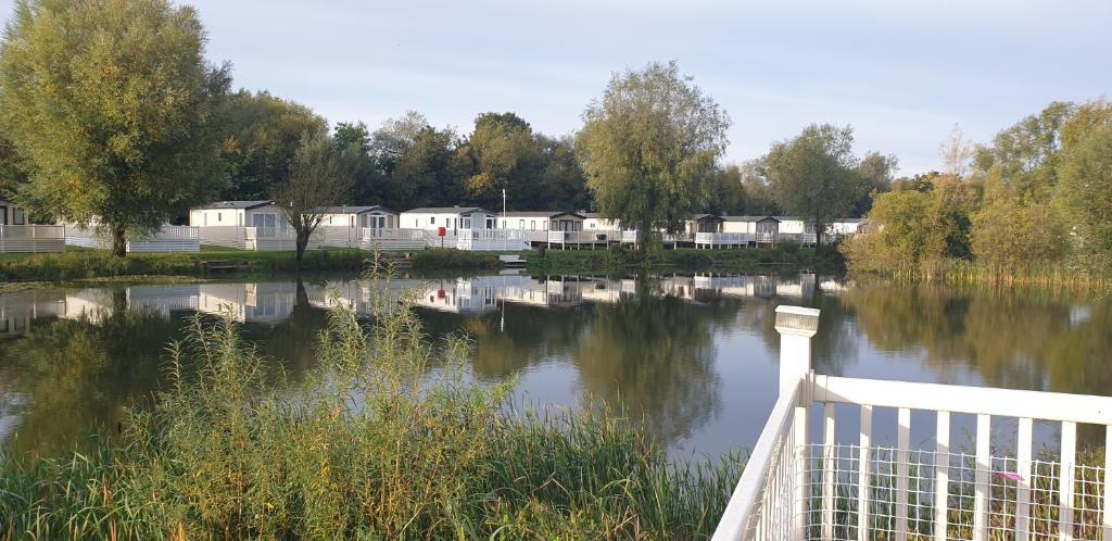 a view of a river with houses in the background at Lakeside Cotswold Holiday Home in Cirencester