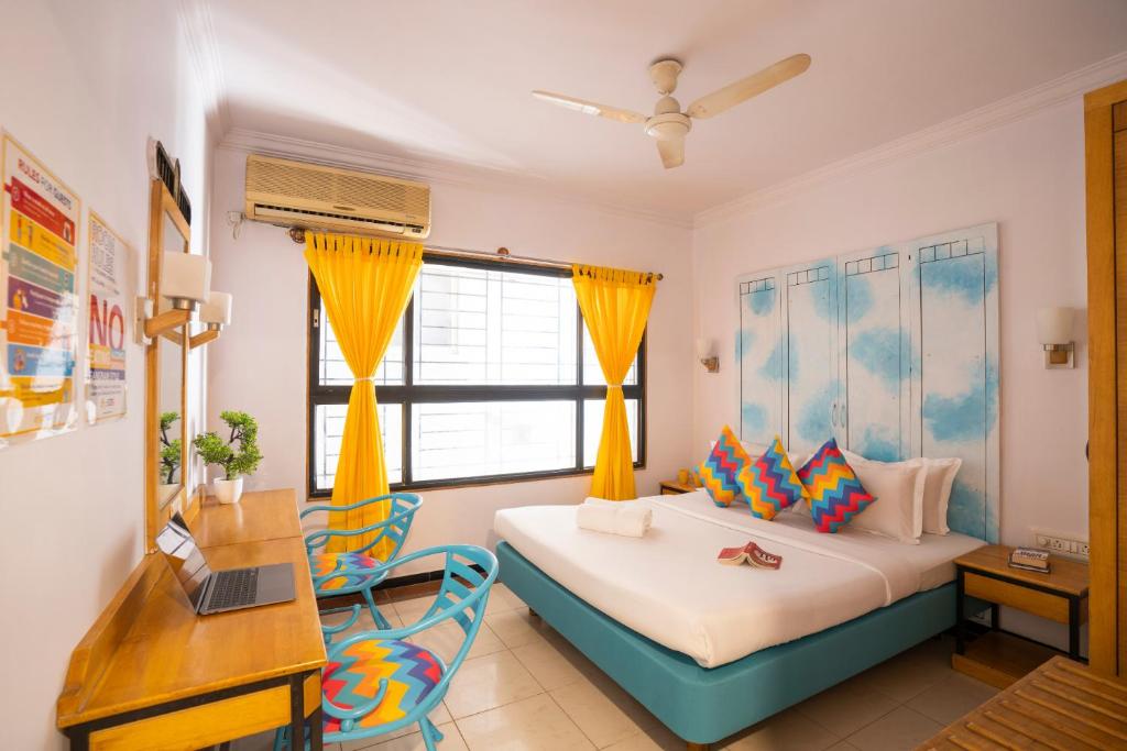 a bedroom with a bed and a desk and a laptop at goSTOPS Bengaluru, Gandhi Nagar Majestic in Bangalore