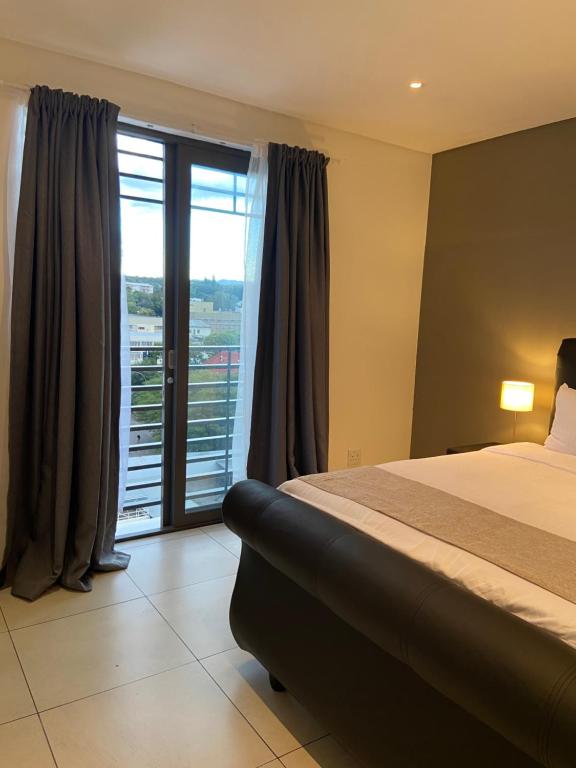 a hotel room with a bed and a large window at Worm Wood Homes at City Junction in Windhoek