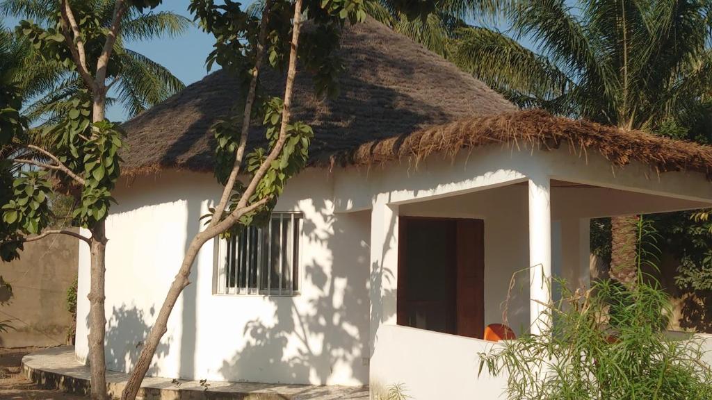 a small white house with a thatch roof at Case traditionnelle diola au bord de l'océan in Cap Skirring