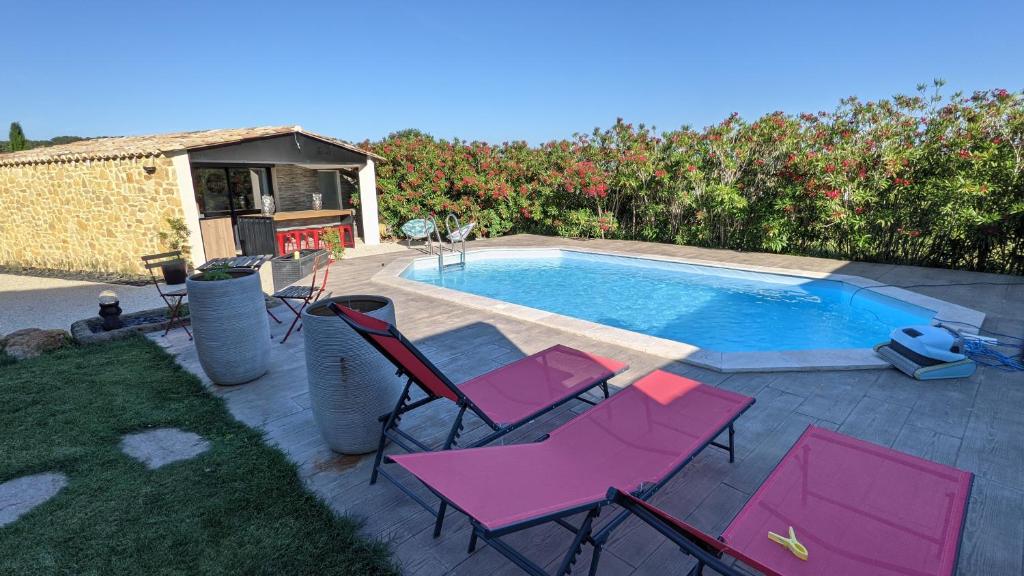 a group of pink chairs and a swimming pool at Dépendance en Provence entre Orange et Avignon in Piolenc