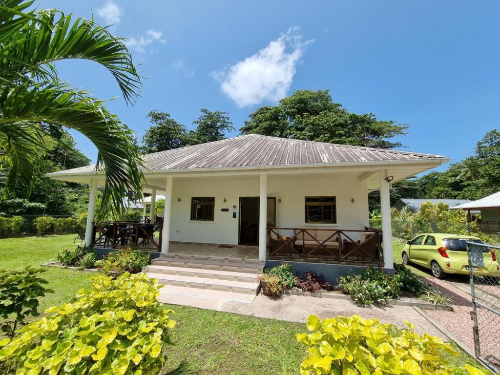 a small white house with a palm tree at Villa Laure in Grand'Anse Praslin