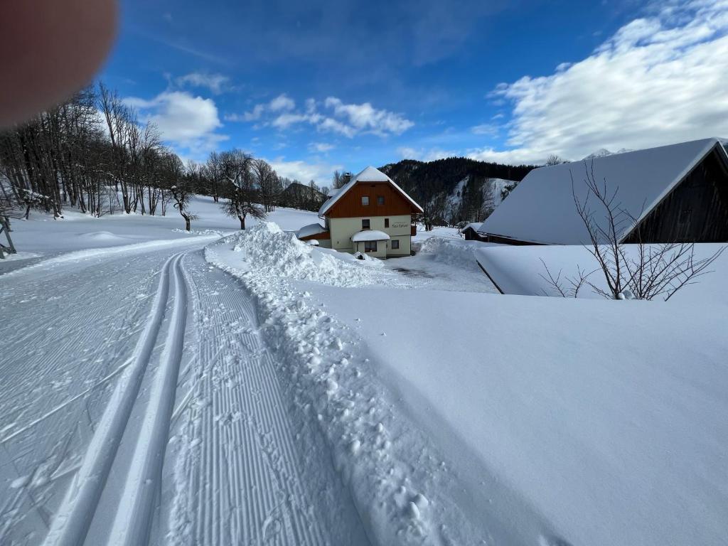 een weg bedekt met sneeuw naast een schuur bij Ferienwohnung Ketterer in Ramsau am Dachstein
