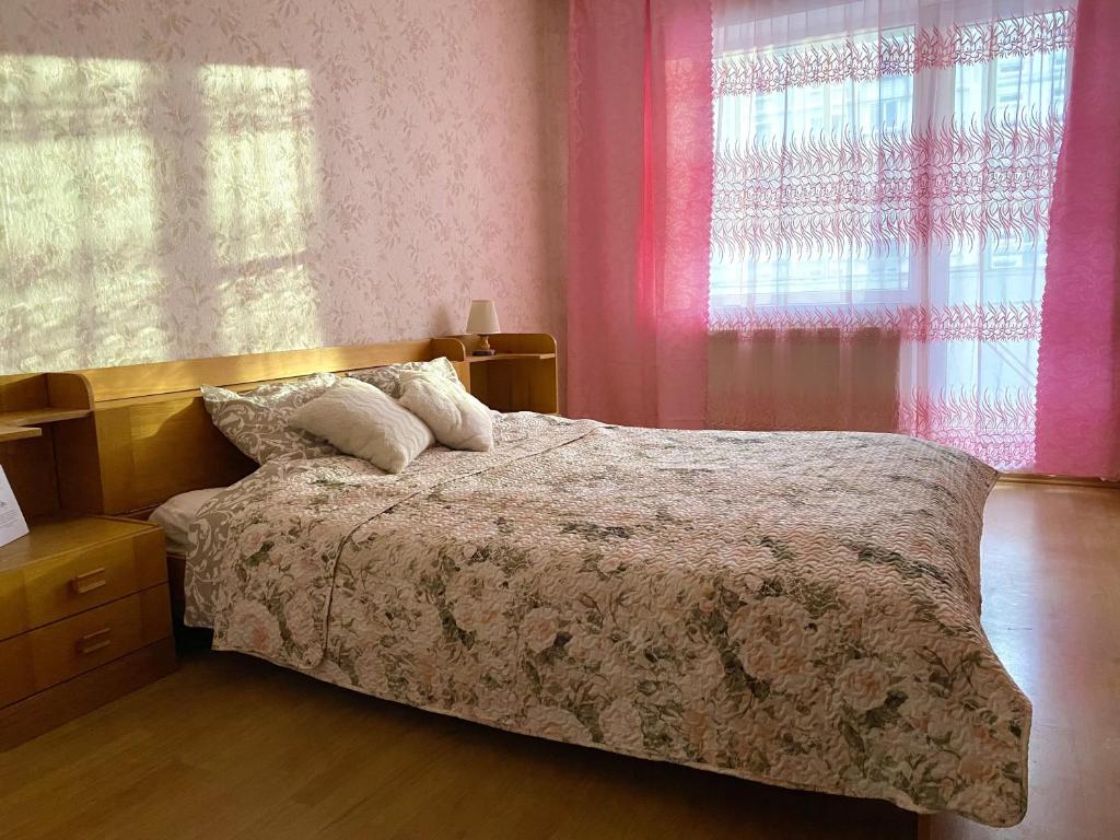 a bedroom with a bed with pink walls and windows at Spacious 3-Room Apartment & Parking in Rīga
