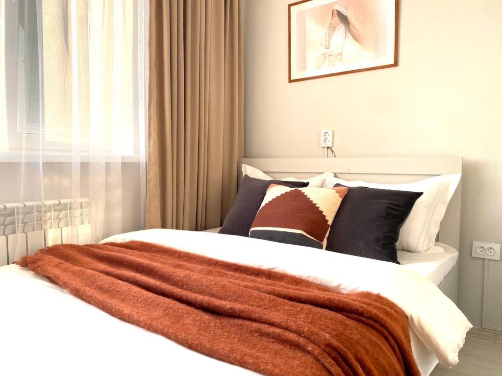 um quarto com uma cama com um cobertor em Skandi em Almaty