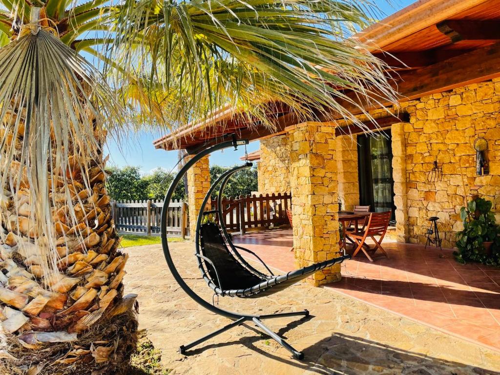 a hammock on a porch of a house with a palm tree at Villa Oleandra Relais in Partinico