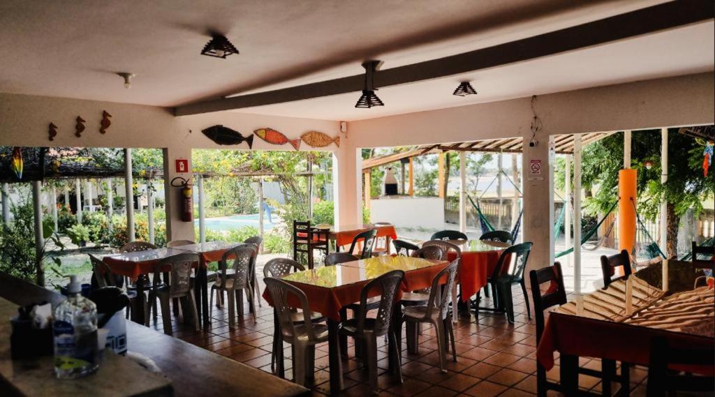 um restaurante com mesas, cadeiras e janelas em Pousada Sol Dourado em Jiloca de Jericoacoara