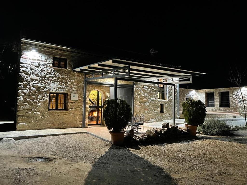 una casa de piedra por la noche con dos plantas delante de ella en Viña Las Olivas en Andújar