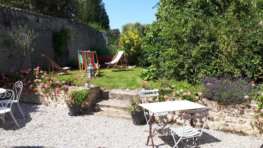 a garden with a table and chairs and flowers at Les Lilas de Bellefontaine in Bayeux