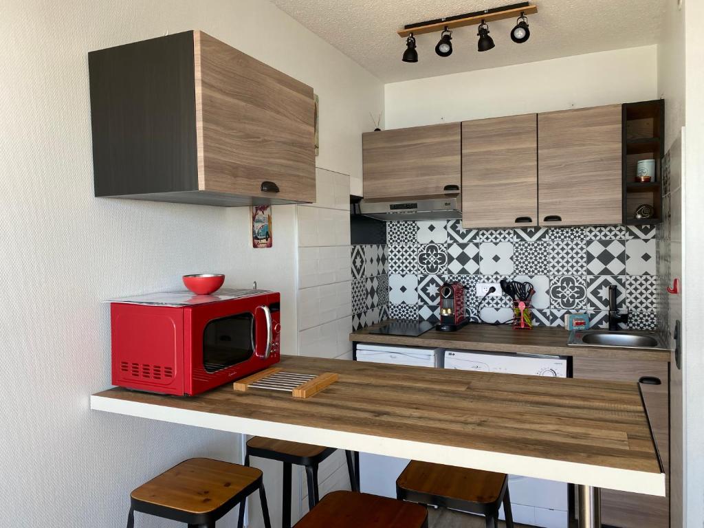 een keuken met een rode magnetron op een aanrecht bij LACANAU FRONT DE MER in Lacanau