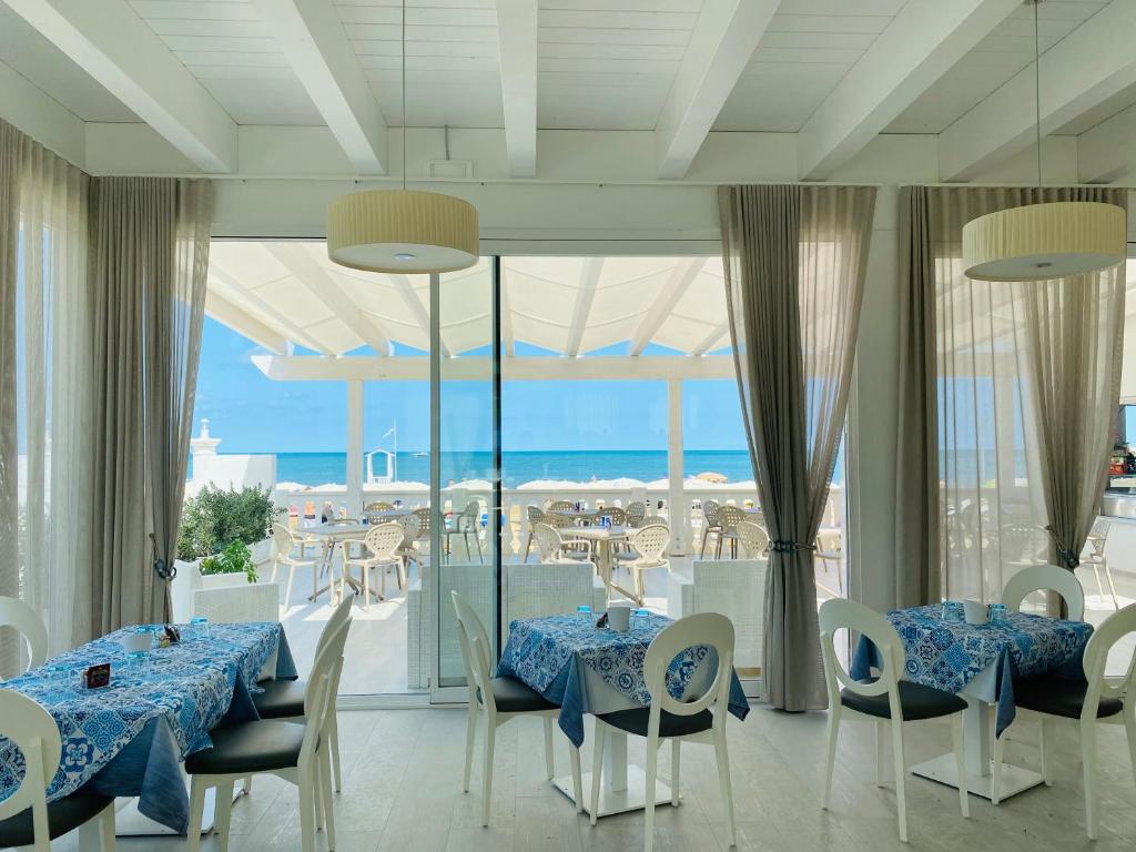 een eetkamer met 2 tafels en uitzicht op de oceaan bij Hotel Corona Beach Peschici in Peschici