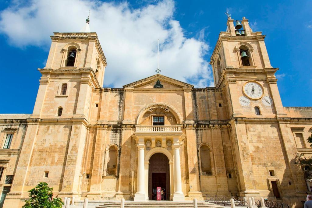 uma velha igreja com duas torres e um relógio em No. 31 in Valletta em Valeta