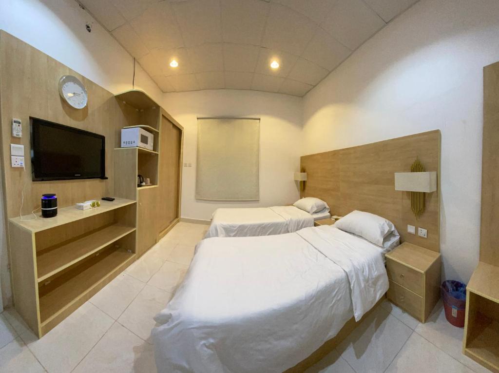 a hotel room with two beds and a television at شقق شاطئ النخيل in Umm Lujj