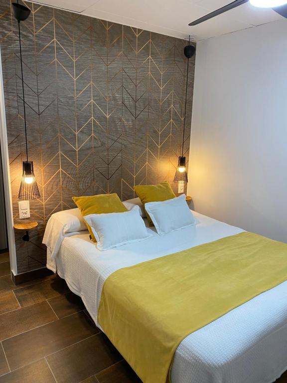 a bedroom with a large bed with yellow sheets at Pension Rovior in Calafell