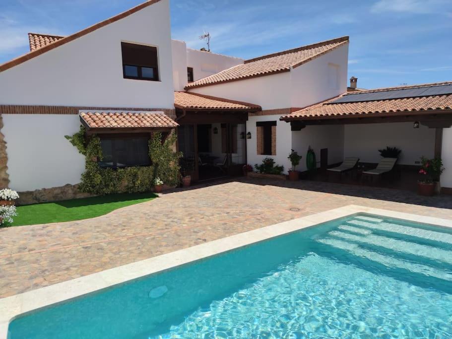 a villa with a swimming pool in front of a house at LA CASA DE ELENA in Villarrubia de los Ojos