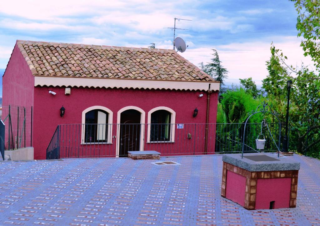 un bâtiment rouge avec une clôture devant lui dans l'établissement Agriturismo Dolcetna, à SantʼAlfio