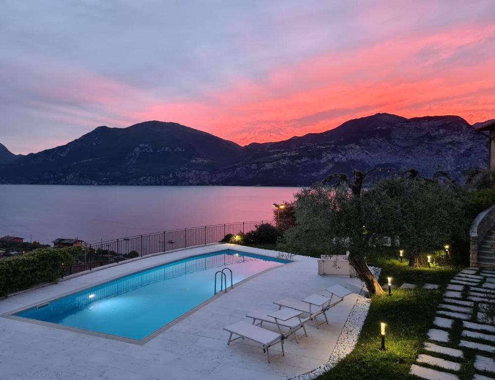 a pool with a view of a lake at sunset at Villa Borgo Borago in Brenzone sul Garda