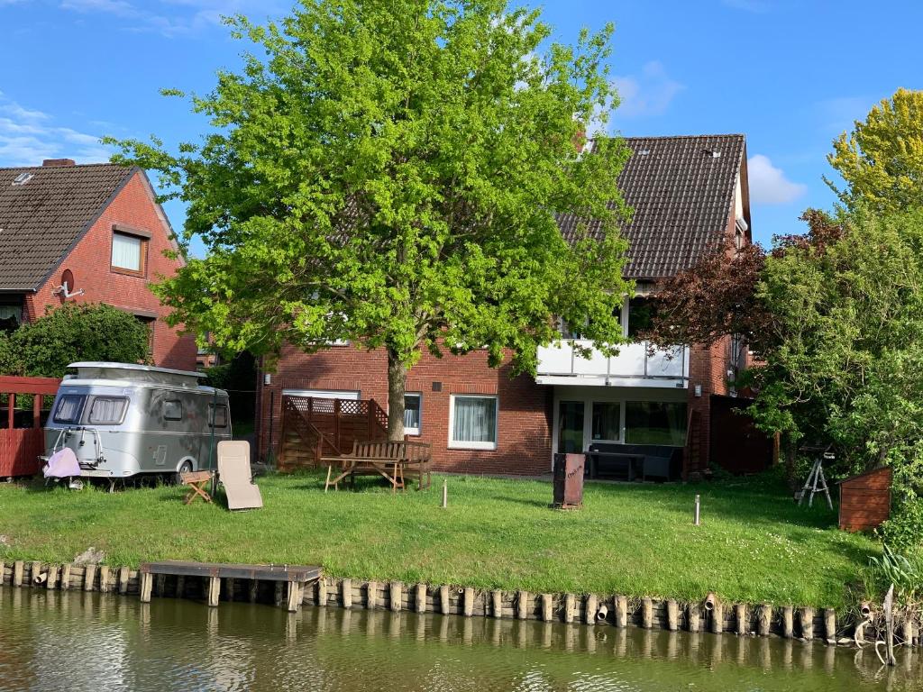 een camper geparkeerd naast een huis met een boom bij Ferienwohnungen direkt am Wasser in Glückstadt in Glückstadt