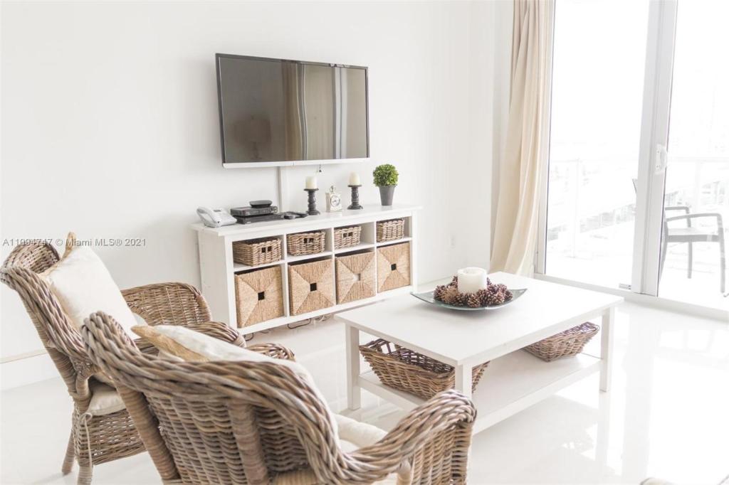 a living room with a white table and wicker chairs at DISFRUTA SUNNY ISLES OCEAn 1206 STR-02637 in Miami Beach