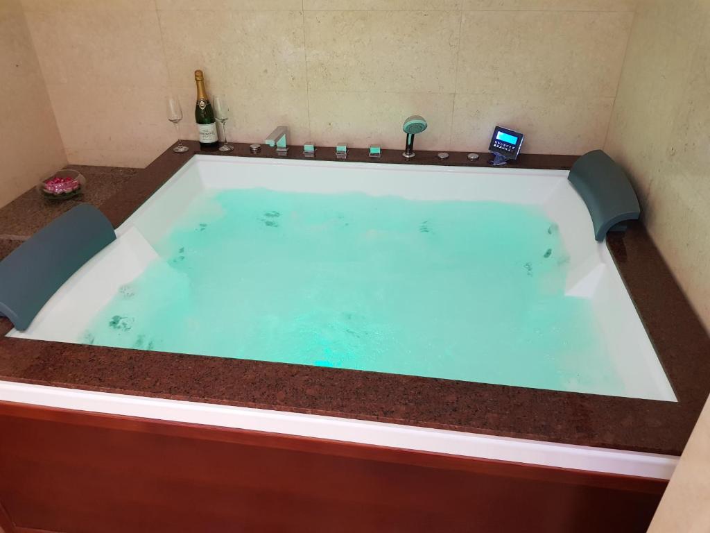 une baignoire jacuzzi dans une chambre avec une bouteille de vin dans l'établissement Mega Mall Monza Super Spa, à Bucarest