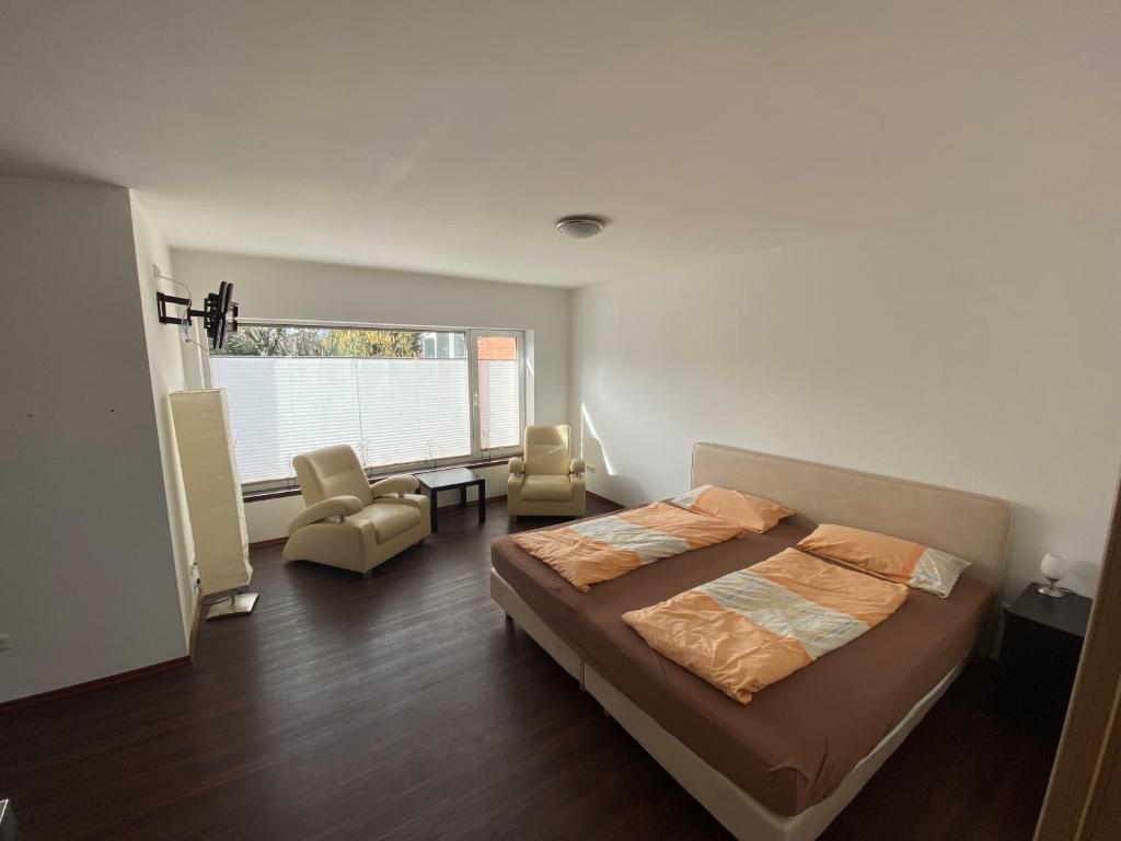 ein Schlafzimmer mit einem Bett, einem Stuhl und einem Fenster in der Unterkunft Pension Haselmann in Münster