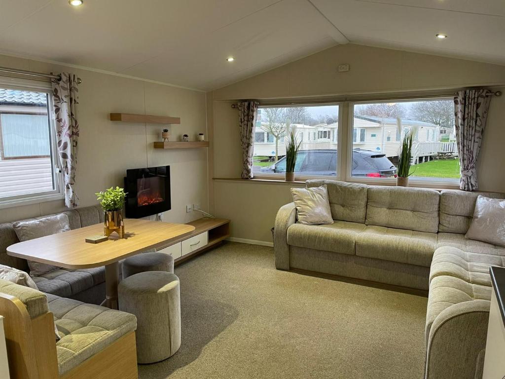 a living room with a couch and a table at Coastal retreats, Beech rise, primrose valley in Filey
