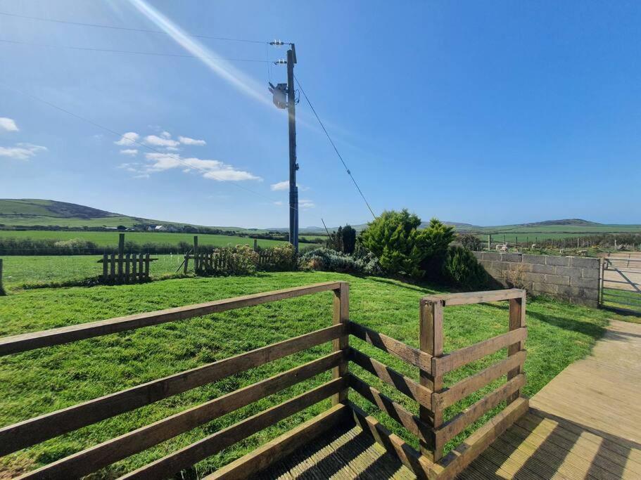 a wooden fence in front of a green field at On farm Chalet, sleeps 6, Rhoshirwaun in Aberdaron