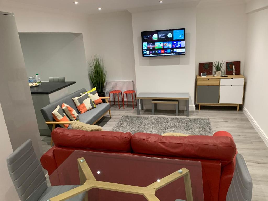 a living room with a red couch and a tv at Beautiful 5 Bedrooms house, free parking & Wifi Corporate, Contractors, Family relocation, CONTACT US FOR LONG TERM RATE in Dartford
