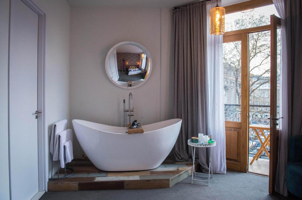 een badkamer met een groot bad en een spiegel bij Redrum Tbilisi Boutique Hotel in Tbilisi City
