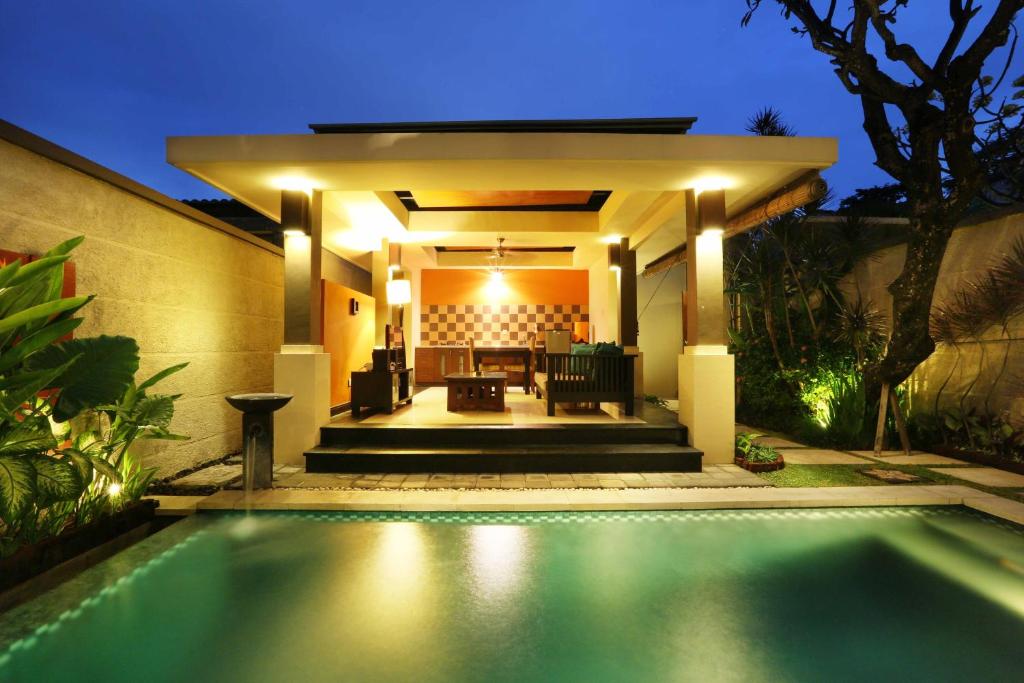 a swimming pool in front of a house at night at The Bali Bliss Villa in Seminyak