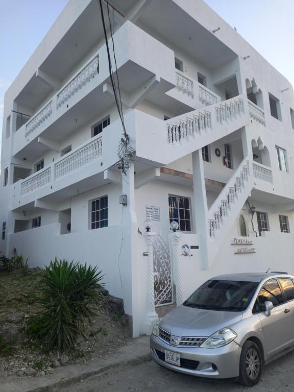un coche aparcado delante de un edificio blanco en Canadian Standard Villa Guesthouse, en Montego Bay