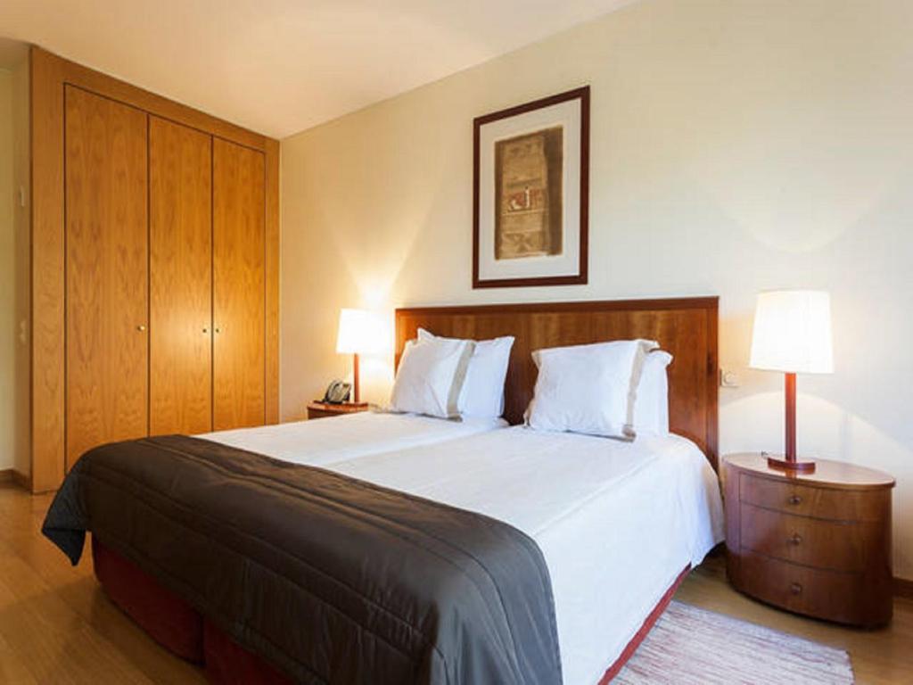 - une chambre avec un grand lit blanc et deux lampes dans l'établissement Stay in the heart of Lisbon- Altis Suites Hotel 4*, à Lisbonne